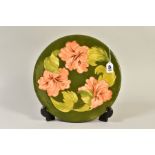 A MOORCROFT POTTERY CHARGER, coral hibiscus design on a green ground, painted signature and