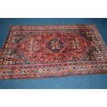 A 20TH CENTURY WOOLLEN AFSHAR RED GROUND RUG, 262cm x 173cm