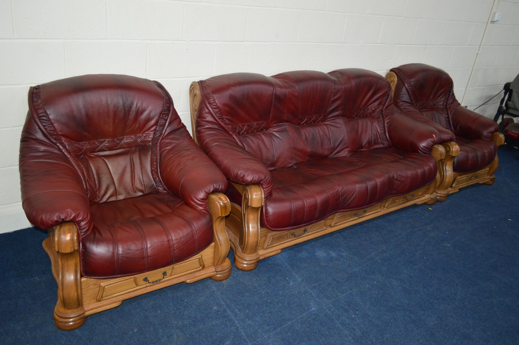 A RED LEATHER AND GOLDEN OAK THREE PIECE LOUNGE SUITE comprising of a three seater settee and a pair - Image 2 of 2