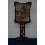 A VICTORIAN ROSEWOOD NEEDLEWORK FIRESCREEN, of a seated lady reading within a foliate scrolled frame