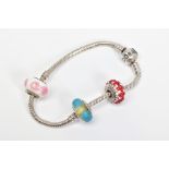 A PANDORA CHARM BRACELET, suspending one glass Pandora charm and two non designer charms, bracelet