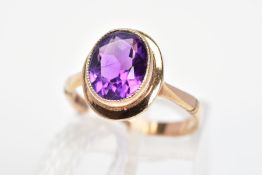 A 9CT GOLD AMETHYST RING, the oval amethyst in a millegrain setting to the plain surround and
