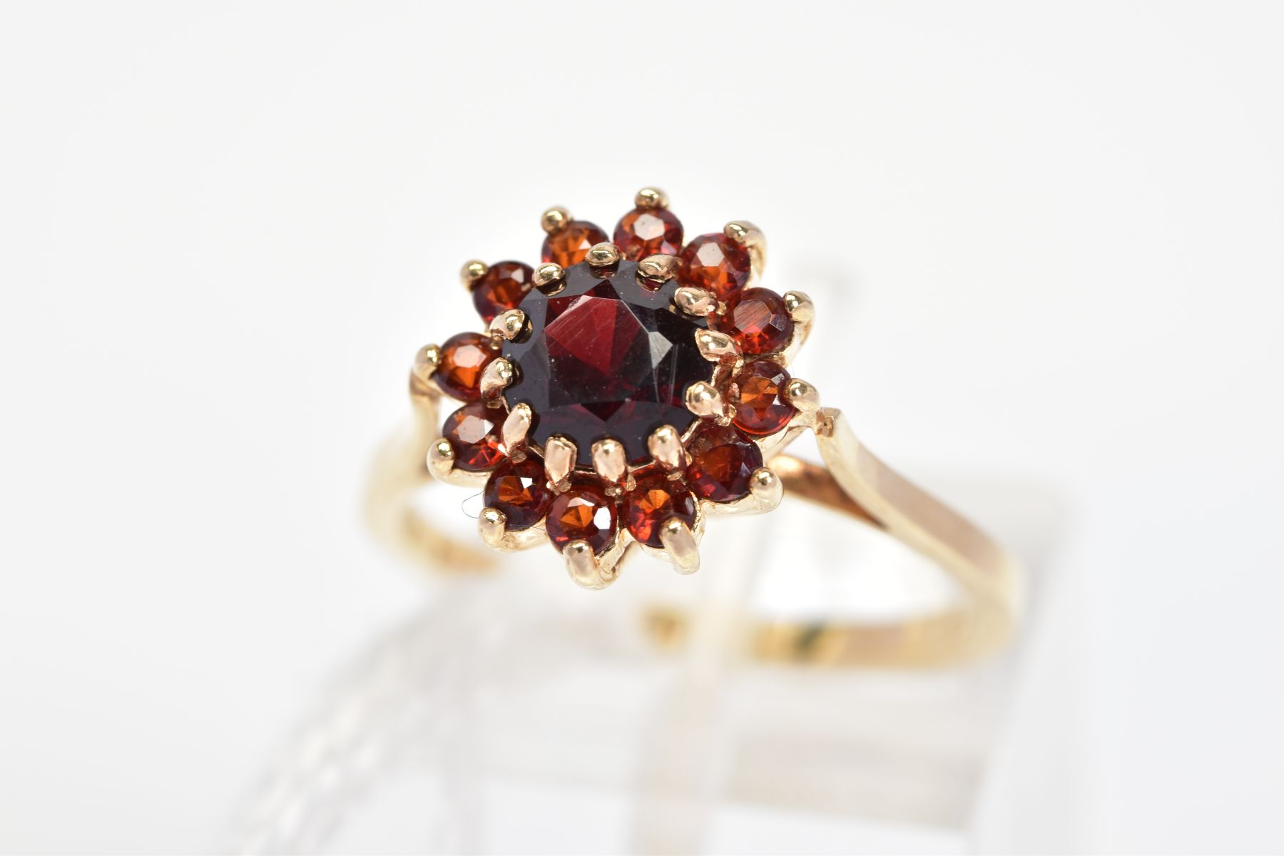 A 9CT GOLD RED PASTE CLUSTER RING, the central circular red paste within a circular red paste