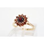 A 9CT GOLD RED PASTE CLUSTER RING, the central circular red paste within a circular red paste