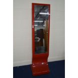 A MODERN SHAPED GLASS CHEVAL MIRROR on a bright red ground, width 40cm x height 165cm