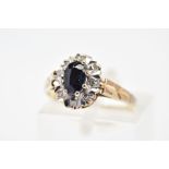 A 9CT GOLD SAPPHIRE AND DIAMOND RING, of cluster design set with a central oval sapphire and diamond
