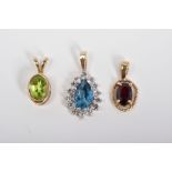 THREE PENDANTS, the first of 9ct gold set with an oval cut garnet within a rope twist surround, with