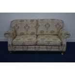 A MODERN BEIGE FLORAL UPHOLSTERED TWO SEATER SETTEE on brass casters