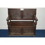 AN EARLY 20TH CENTURY OAK MONKS BENCH, with twin foliate carved panels to the hinged top and front