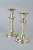 A NEAR PAIR OF EDWARDIAN SILVER CANDLESTICKS, concentric band decoration to rims, inverted conical