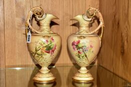 A PAIR OF ROYAL WORCESTER BLUSH IVORY EWERS, florally decorated with gilt detailing, the body raised