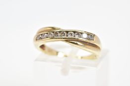 A 9CT GOLD RING, the cross over design set with a diagonal line of channel set circular cubic