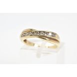 A 9CT GOLD RING, the cross over design set with a diagonal line of channel set circular cubic