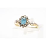A 9CT GOLD TOPAZ AND DIAMOND CLUSTER RING, the oval topaz in a claw setting within a single cut