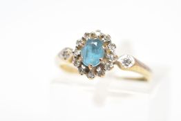 A 9CT GOLD TOPAZ AND DIAMOND CLUSTER RING, the oval topaz in a claw setting within a single cut