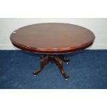 AN EDWARDIAN MAHOGANY OVAL TILT TOP TABLE on carved shaped quadraped legs and brass casters