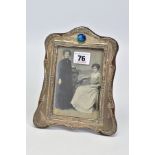 AN EARLY 20TH CENTURY SILVER FRONTED PHOTO FRAME, with embossed floral and foliate detail and a