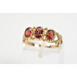 A 9CT GOLD PASTE RING, designed as three oval red pastes to the bifurcated shoulders with further