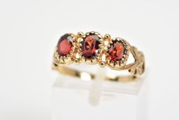 A 9CT GOLD PASTE RING, designed as three oval red pastes to the bifurcated shoulders with further