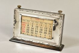 A GEORGE V STYLE MOUNTED PERPETUAL CALENDAR, of rectangular form, wavy edge to the frame, bears