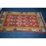 A WOOLLEN RED AND ORANGE GROUND RUG, 220cm x 124cm