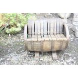 A BOURBON WHISKEY BARREL GARDEN BENCH with barrel staves as seat, back and feet, length 88cm