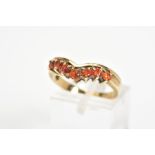 A 9CT GOLD GEM RING, the v-shape ring is claw set to the front with seven circular orange gems,