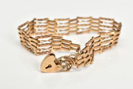 A YELLOW METAL GATE BRACELET, links with twist design, fitted with a gold heart padlock clasp,