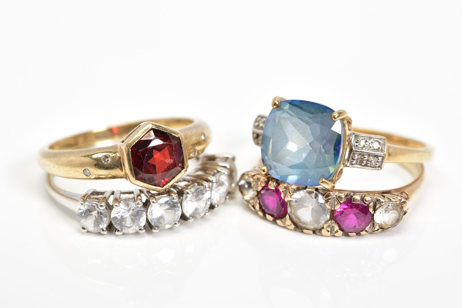 FOUR 9CT GOLD GEM SET RINGS, the first collet set with a central hexagonal garnet and flush set with