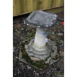 A COMPOSITE BIRD BATH with an octagonal top and base joined by a tapered round stem standing on an