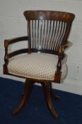 AN EARLY 20TH CENTURY WALNUT SPINNING OFFICE CHAIR, with a spindle back, turned arm rests, on four