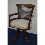 AN EARLY 20TH CENTURY WALNUT SPINNING OFFICE CHAIR, with a spindle back, turned arm rests, on four