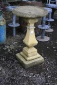 A COMPOSITE TWO PIECE BIRD BATH with a stepped and detailed base, square baluster tapering stem