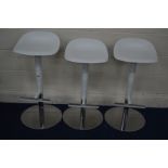A SET OF THREE WHITE PERSPEX SWIVEL BAR STOOLS with footrests on chrome bases