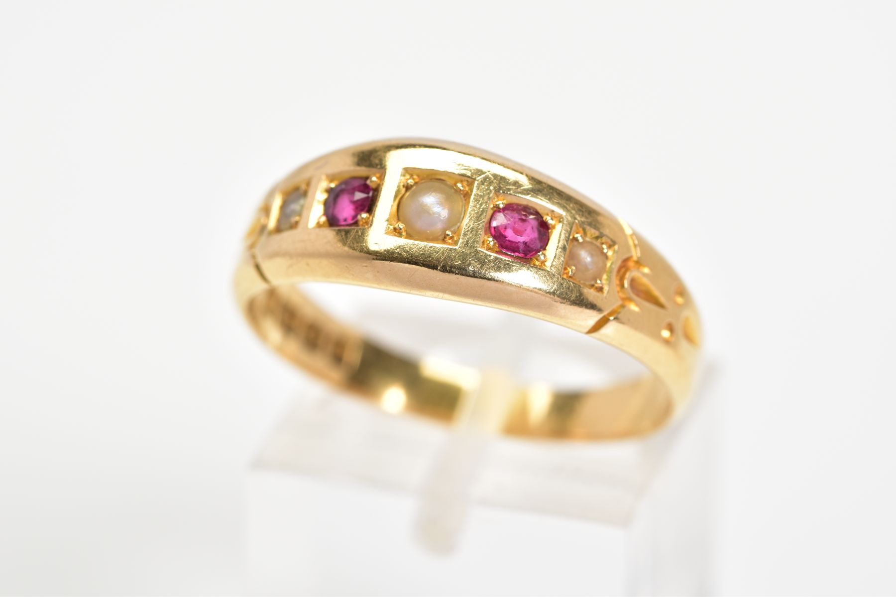 AN EDWARDIAN 18CT GOLD GEM RING, the tapered band set with three split pearls interspaced by red