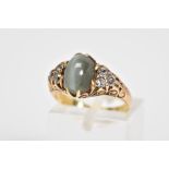 A CATS EYE CRYSOBERYL AND DIAMOND RING, designed with a central oval cut cats eye chrysoberyl