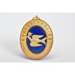 A SILVER GILT MEDALLION, of oval shape featuring a blue enamel centre with bird embellishment and