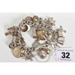 A VINTAGE CHARM BRACELET WITH TWENTY NINE CHARMS, to include a hinge lid lamp, bird cage, Broadway