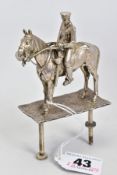 A SILVER HORSE AND JOCKEY, designed as a horse with regimental rider on a plate of silver plate,