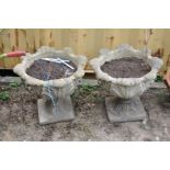 A PAIR OF COMPOSITE GARDEN URNS in the form of acanthus leaf bowl on top of a square foot,