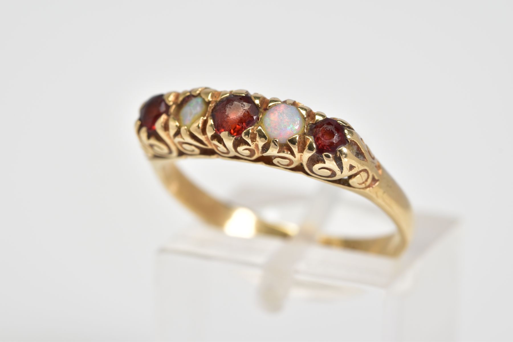 A 9CT GOLD RING, designed as a row of three circular cut garnets interspaced by two circular opals