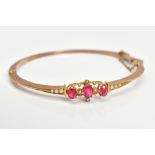 AN EARLY 20TH CENTURY GOLD SPLIT PEARL AND GARNET TOPPED DOUBLET FANCY BANGLE, measuring