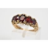A 9CT GOLD FIVE STONE RING, set with five oval cut garnets, scrolling detail to gallery and