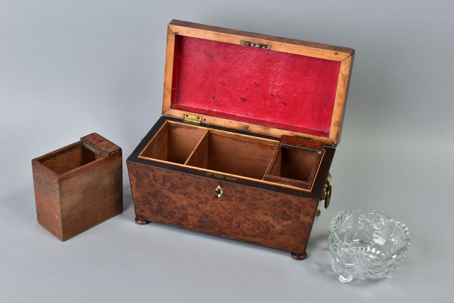 AN EARLY VICTORIAN AMBOYNA TEA CADDY, of sarcophagus form, gilt metal ring handles to sides, bun