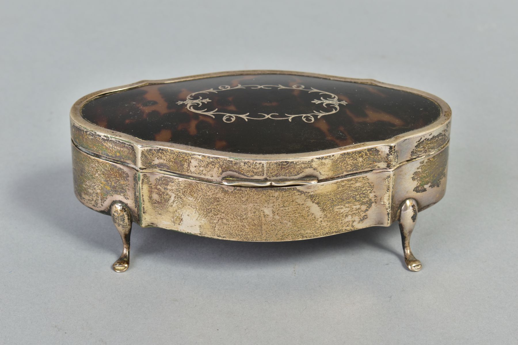 AN EARLY 20TH CENTURY SILVER AND TORTOISESHELL PIQUE WORK TRINKET BOX, of shaped oval form,