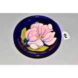 A MOORCROFT POTTERY SHALLOW BOWL, blue ground with pink magnolia design, painted signature and