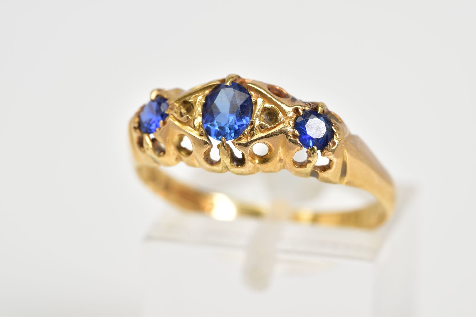 AN EARLY 20TH CENTURY BOAT RING, set with three graduated oval cut, assessed as synthetic