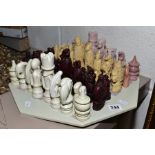 A CARVED HARDSTONE CHESS SET, the pieces are stylised African designs, together with a resin set