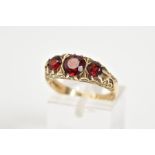 A 9CT GOLD BOAT RING, set with three graduated circular garnets within a scrolling detail gallery,