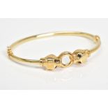 A 9CT GOLD BANGLE, a hinge open bangle featuring two panther heads set with black gemstone eyes